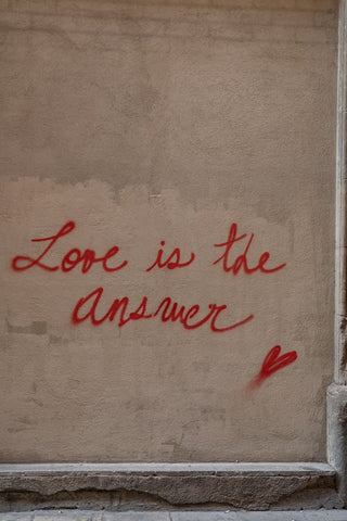 "Love is the answer" spray painted in red with a heart on a concrete wall