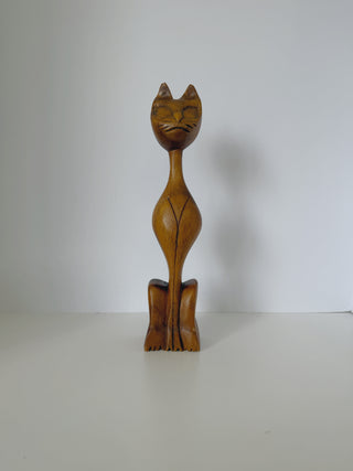 Vintage handcarved wooden cat statue front view showing elongated body, pointed ears, carved whiskers and facial features on natural wood grain