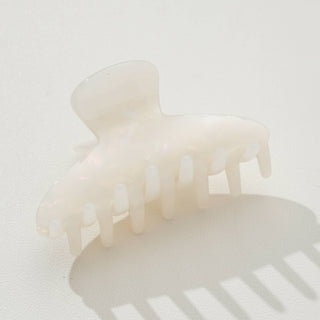 White translucent curved claw clip with teeth visible, side view showing curved shape on neutral background