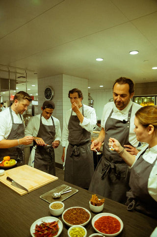 Chef Daniel Humm and culinary team in Eleven Madison Park kitchen tasting and discussing ingredients during product development
