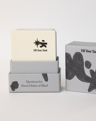 Card deck partially pulled out from packaging showing cream-colored cards with Fill Your Tank logo inside white and gray two-piece box