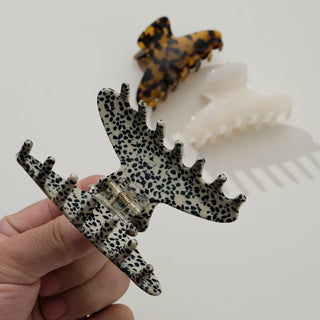 Hand holding leopard print claw clip showing metal clasp mechanism and size scale against fingers
