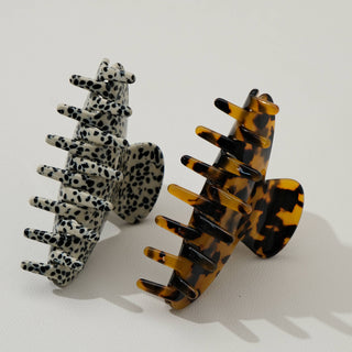 Two curved claw clips standing upright showing leopard print and tortoiseshell patterns with white clip in background