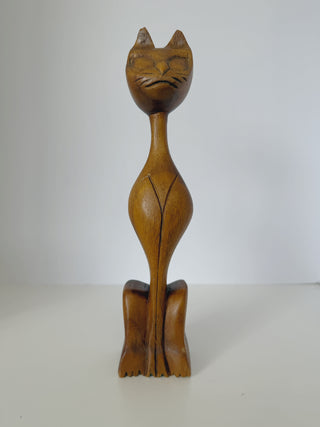 Close-up front view of vintage wooden cat sculpture highlighting carved facial features, whiskers, closed eyes and pointed ears with natural wood patina