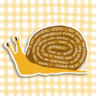 Yellow and brown die-cut snail sticker with white spiral text about capitalism and natural speed on yellow gingham background