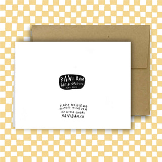 Back of white greeting card showing Rani Ban Art & Objects logo and shop information, displayed with kraft envelope on checkered background