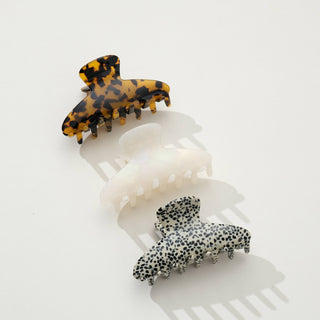 Tortoiseshell and white claw clips arranged diagonally showing size comparison and pattern details with shadows