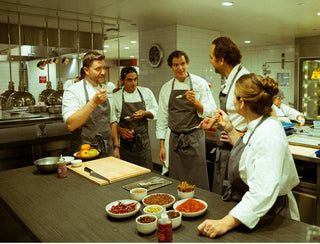 Chef Daniel Humm and kitchen team at Eleven Madison Park discussing chili oil creation with various spices displayed on counter