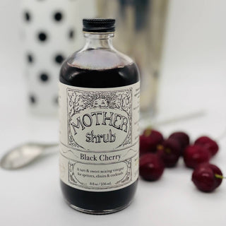 MOTHER shrub Black Cherry 8oz bottle with vintage-style label on white marble counter with fresh cherries and polka dot towel in background