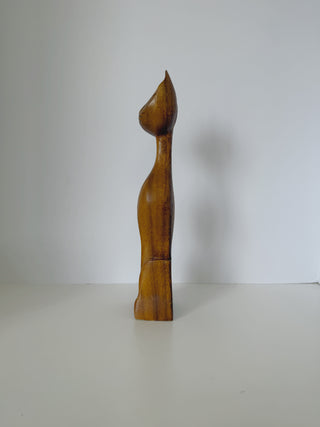Right side angle of handcarved wooden cat figurine showing smooth carved curves and natural wood color variations from light to darker tones