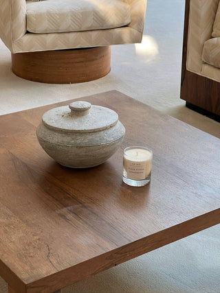 Candle on wood table with vessel next to it