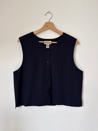 Front view of vintage navy wool vest on wooden hanger showing button-front closure and tailored silhouette against neutral background