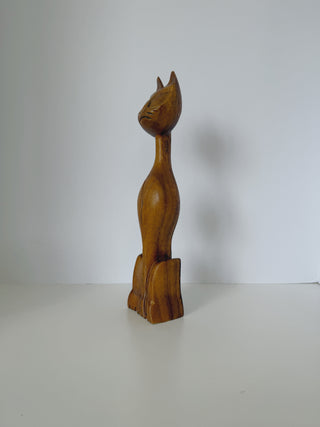 Side profile view of vintage wooden cat sculpture displaying curved silhouette, long neck and carved details on warm honey-toned wood