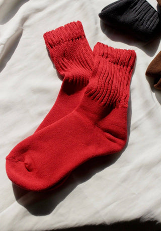 Red Fifi socks by Na Nin layed flat on a light-colored surface