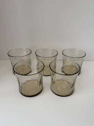 Front view of five vintage smoked glass tumblers in gray tone with textured sides arranged in two rows