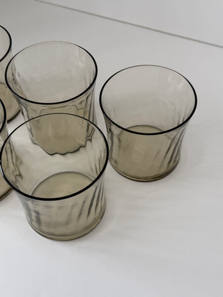 Overhead angled view of vintage smoked glass tumblers showing dark rim detail and varied wave patterns