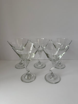 Front view of five vintage twisted stem martini glasses arranged in two rows on white surface