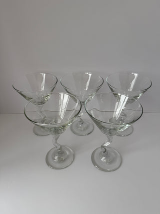 Overhead angled view of five vintage martini glasses with zig zag twisted stems displaying conical bowl shapes