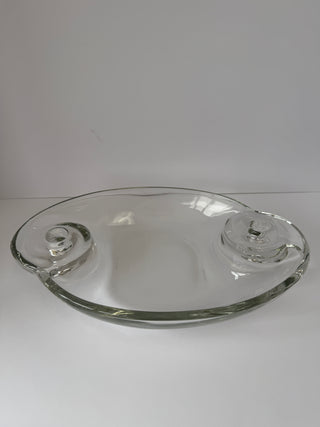 Angled view of vintage glass centerpiece displaying smooth oval surface and sculptural candle holder details