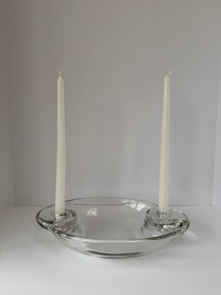 Vintage glass centerpiece styled with two white taper candles inserted in spiral holders against white background