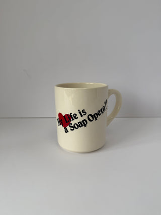 Vintage cream ceramic mug with 'My Life is a Soap Opera!' text in red and black, photographed against white background from front angle