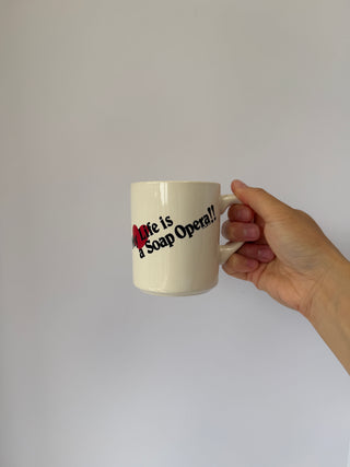 Hand holding vintage Life is a Soap Opera mug demonstrating size and comfortable grip of ceramic handle