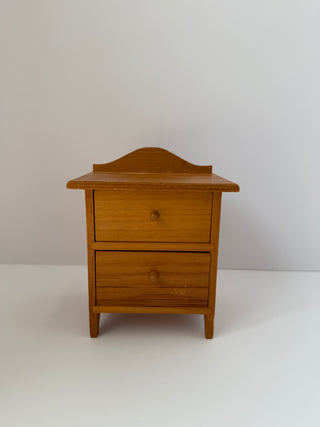 Front view of vintage wooden jewelry box dresser with closed drawers, showing curved top backsplash and wooden knob pulls on neutral background