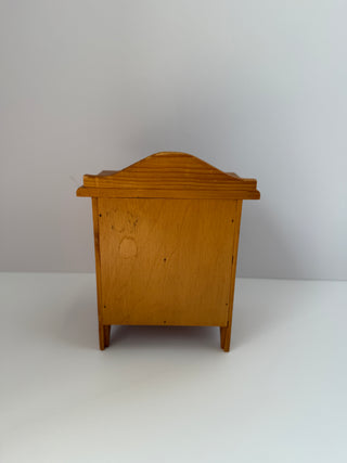Back view of vintage wooden jewelry box dresser showing curved top detail, wooden construction, and painted or marked surface on rear panel
