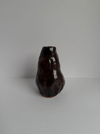 Side view of vintage wabi-sabi ceramic vase in deep aubergine color, displaying textured vertical ridges and teardrop silhouette on white surface