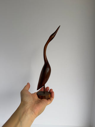 Hand holding vintage carved wood crane figurine showing scale and detailed craftsmanship of bird sculpture