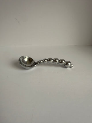 Side view of vintage silver spoon showing curved bowl and decorative ball-shaped beaded handle