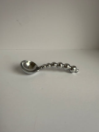 Close-up side angle of pewter spoon displaying polished finish and unique graduated bead handle design