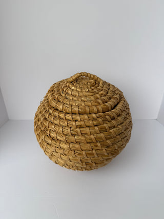Top view of vintage round woven basket showing spiral weave pattern on lid with wrapped handle at center