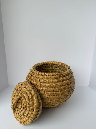 Vintage woven basket with lid removed, showing hollow interior and round bowl shape with natural straw weaving