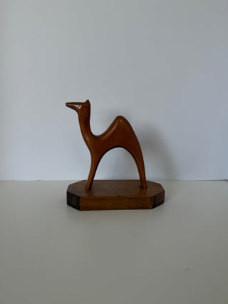 Vintage handmade wood camel sculpture with single hump on octagonal wooden base, front angled view against white background