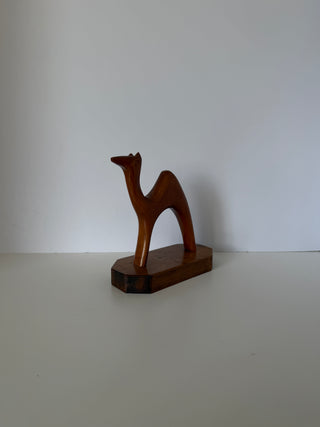 Handcarved wooden camel figurine showing left side profile with elongated neck and minimalist abstract form