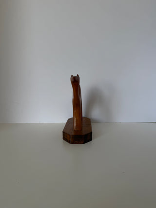 Back view of vintage wood camel sculpture displaying narrow rectangular body and pointed ears on octagonal wooden platform