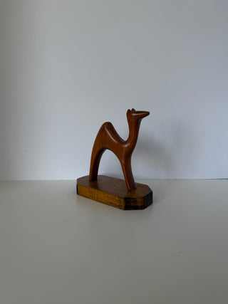 Three-quarter front view of mid-century wooden camel sculpture showing smooth carved details and arched legs