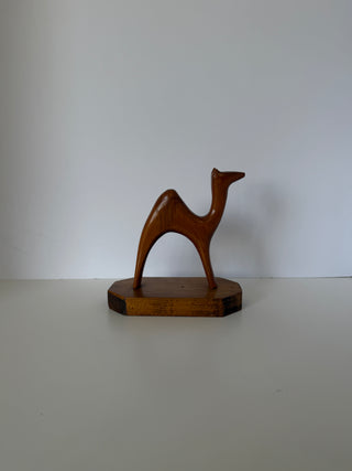 Front angle of handmade wood camel figurine highlighting graceful neck curve and minimalist carved form on wood base