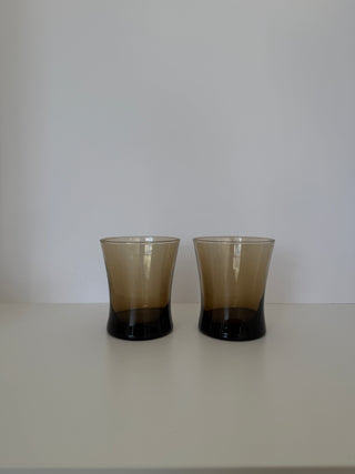 Pair of vintage smoked umber glass tumblers with dark brown bases displayed side by side on white surface against neutral background