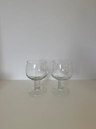 Two vintage French chunky wine glasses with rounded bowls and cylindrical pedestal stems displayed side by side on white surface against neutral background