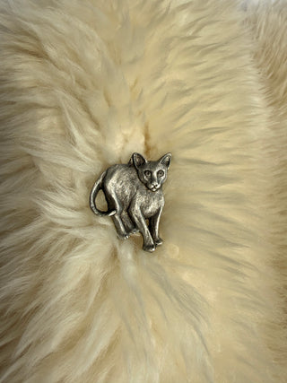 Front view of vintage pewter sitting cat brooch by Rawcliffe centered on fluffy cream fur