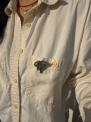 Vintage pewter cat pin by Rawcliffe styled on cream button-up shirt pocket with layered necklaces