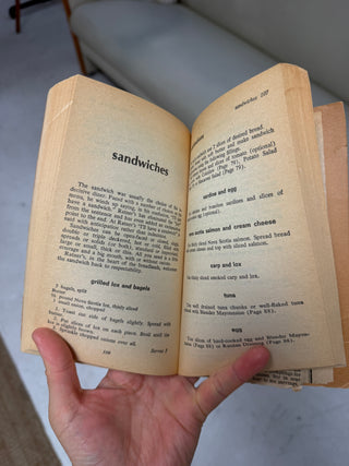 Interior pages of Ratner's Meatless Cookbook opened to sandwiches section on pages 106-107 showing recipes for grilled lox and bagels, sardine and egg, and other dishes