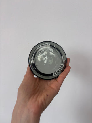 Bottom view of vintage smoked glass tumbler showing black circular base held in palm