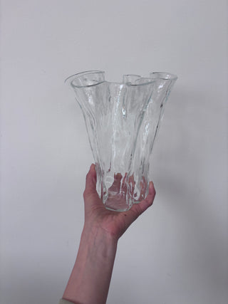 Vintage clear glass fluted vase held in hand against white background, front view showing vertical ridged texture and asymmetrical opening