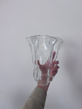 Vintage clear glass fluted vase held upright with hand visible through transparent glass, showing sculptural silhouette and rippled surface