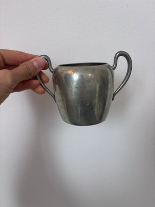 Vintage pewter two-handled sugar bowl held in hand against white background showing fluted body and graceful handles