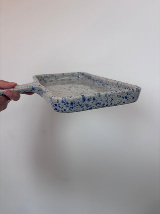 Side profile view of vintage speckled enamel tray showing depth and raised edges