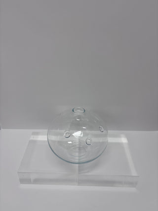 Side angle of vintage clear glass laboratory vessel showing circular portals and architectural form on acrylic base